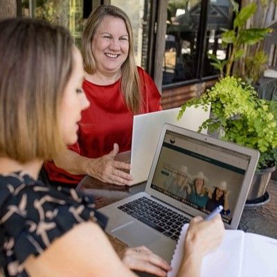 two women chat about SEO over laptops