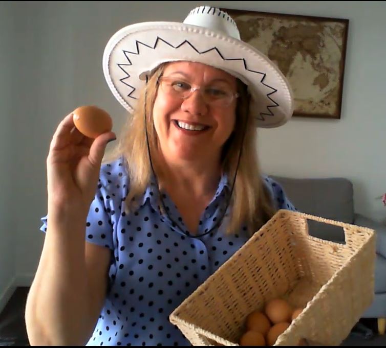 woman in a white cowboy hat holding up a basket of eggs