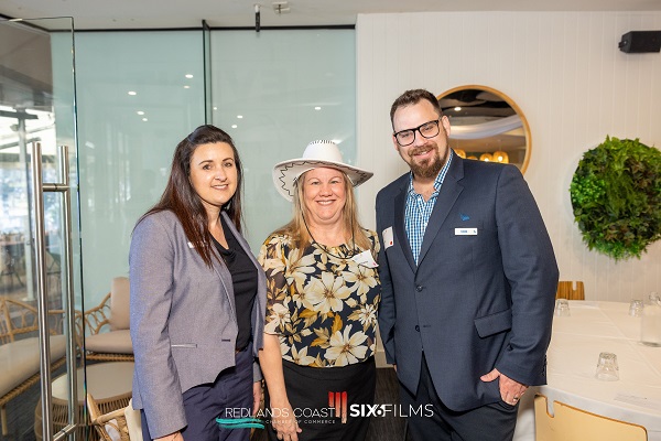 three business people at an event, one wearing a white cowboy hat