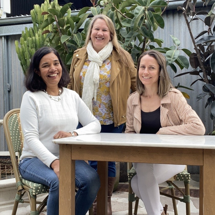 3 women seated around an outdoor table